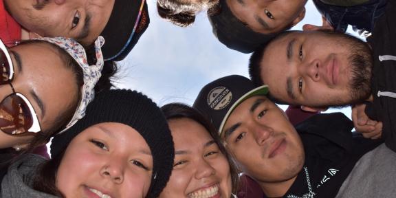 Circle of students looking happily down at the camera